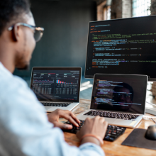 man using multiple computer screens to write code